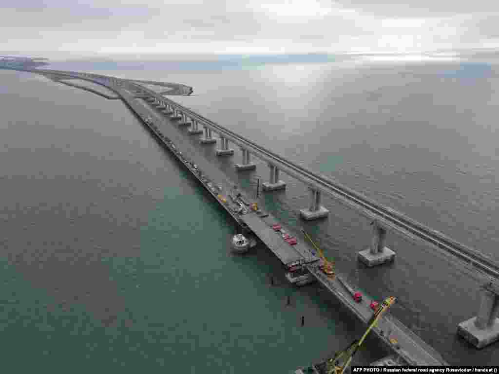 Строительные работы по восстановлению поврежденных пролетов автодорожной части Керченского моста, 9 ноября 2022 года. Керченский мост, открытый президентом России Владимиром Путиным в 2018 году, имеет решающее значение для Москвы с точки зрения логистики и является жизненно важным транспортным звеном для доставки военной техники российским солдатам, воюющим в Украине после полномасштабного военного вторжения России 24 февраля 2022 года  