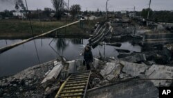 Росія без упину обстрілює Бахмут. На фото: жінка йде через підірваний міст у Бахмуті, 11 листопада 2022 року