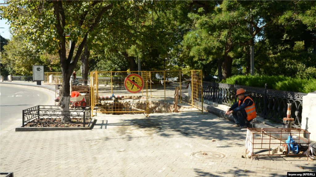 Рабочий отдыхает, сидя на пластиковой трубе на проспекте Нахимова возле транспортной остановки «Приморский бульвар»