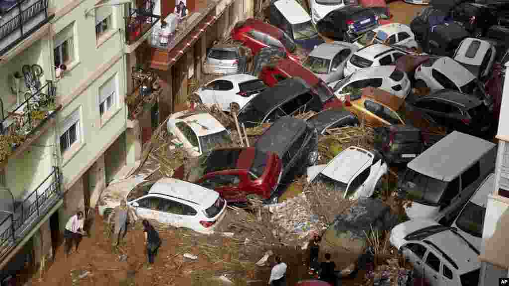 Stanovnici na ulici pored automobila nagomilanih nakon što su ih odnijele poplave u Valensiji, Španija,  30. oktobra 2024. 