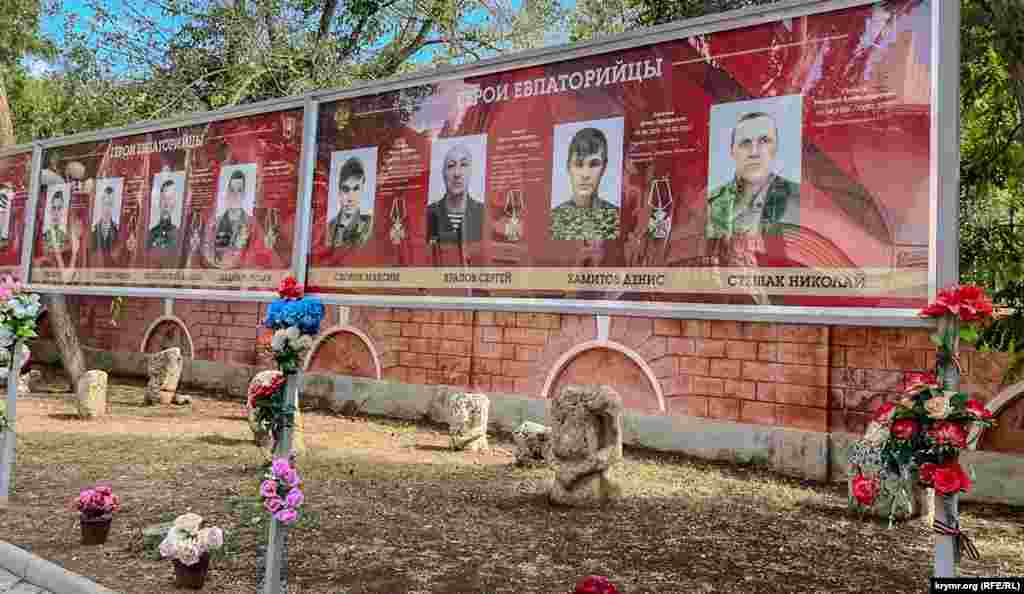 Практически напротив «живой» фотовыставки «Жена и мать героя» – такой же длинный стенд с портретами погибших в СВО евпаторийцев