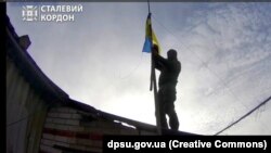 Прикордонник бригади «Гвардії наступу» «Сталевий кордон» піднімає прапор України у прикордонному з РФ населеному пункті Тополі на Харківщині, який перебував у «сірій зоні»