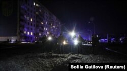 Люди стоять біля кратера, що з'явився після удару російського безпілотника в Харкові, Україна, 30 січня 2024 року