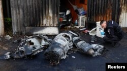 Офіцер поліції оглядає залишки російської крилатої ракети після чергової атаки, 18 травня 2023 року