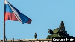 Солдат із рушницею на даху штабу Міноборони Росії в Москві біля встановленої там системи ППО в грудні 2022 року