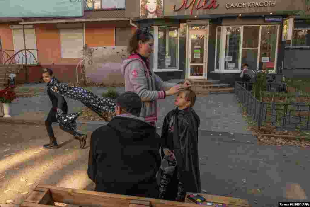 Марина допомагає своїй доньці Анні, 6 років, одягатися на Гелловін, а її чоловік Володимир спостерігає, як їхня донька Дарія бігає в чорній накидці, співаючи: «Я смерть, я ховаюся в тіні». «Ми святкуємо Гелловін, щоб забути війну», – сказав Володимир, усміхаючись сонячному світлу  