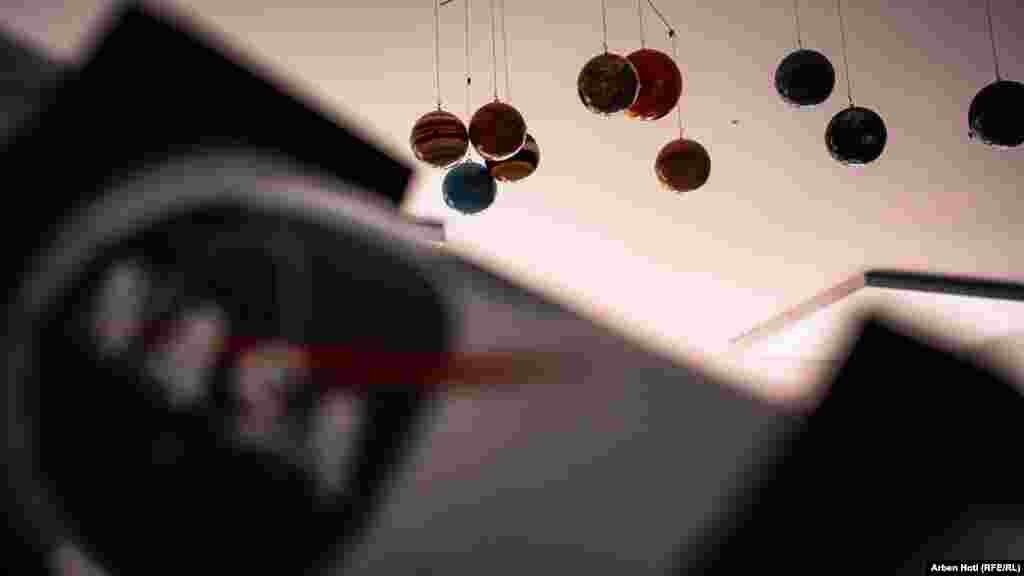 Nebeska tijela vise sa plafona u blizini jednog od doniranih teleskopa koji ima NASA logo.