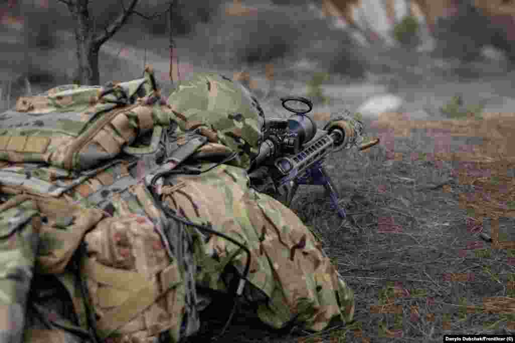 Один з учасників навчання робить постріл із гвинтівки під час тренування.  Еланський каже, що багато колишніх снайперів в Україні перекваліфікувалися на операторів FPV-дронів, але він наполягає на тому, що снайпери, як і раніше, незамінні на полі бою. «Наприклад, ті ж дрони в сильний дощ не літають, а снайпери стріляють за будь-якої погоди», – каже інструктор