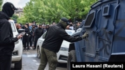 An masked man spray-paints the letter "Z" on to a security forces' vehicle during protests in Zvecan, northern Kosovo, on May 29.