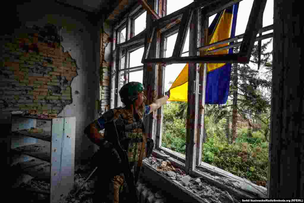 Український військовий із позивним «Борода» з 68-ї окремої єгерської бригади імені Олекси Довбуша розправляє український прапор у звільненому селі Благодатне на Донеччині. Червень 2023 року 