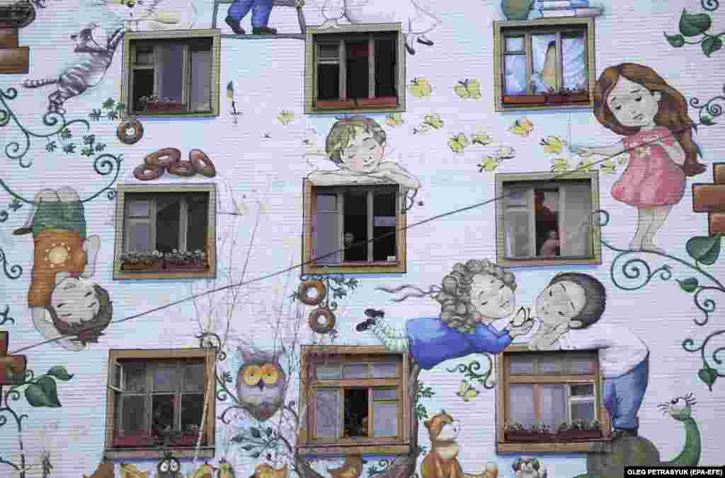 Мешканці будинку прибирають розбите скло з вікон своїх квартир після обстрілу столиці Росією, Київ, 23 січня 2024 року  