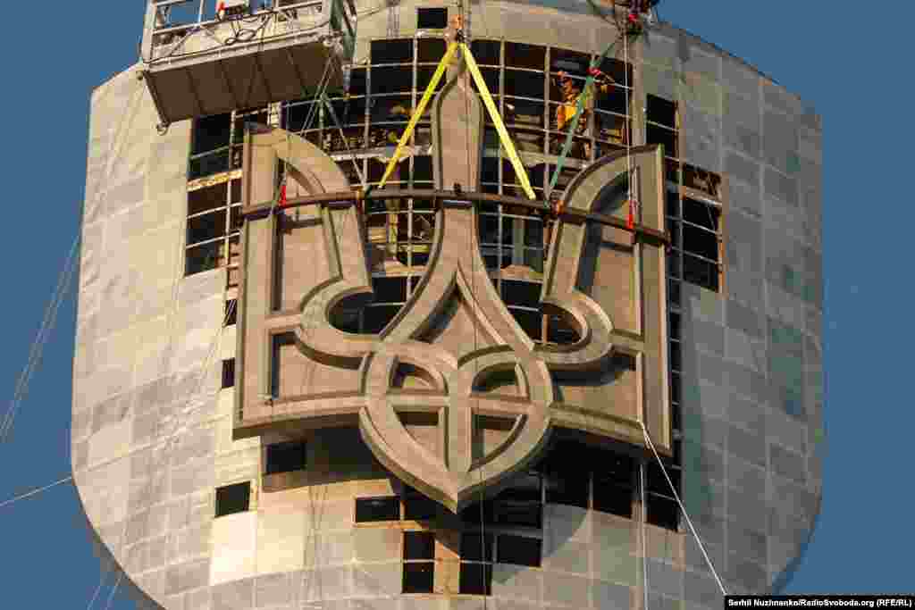 Працівники кріплять Тризуб до щита «Батьківщини-матері»