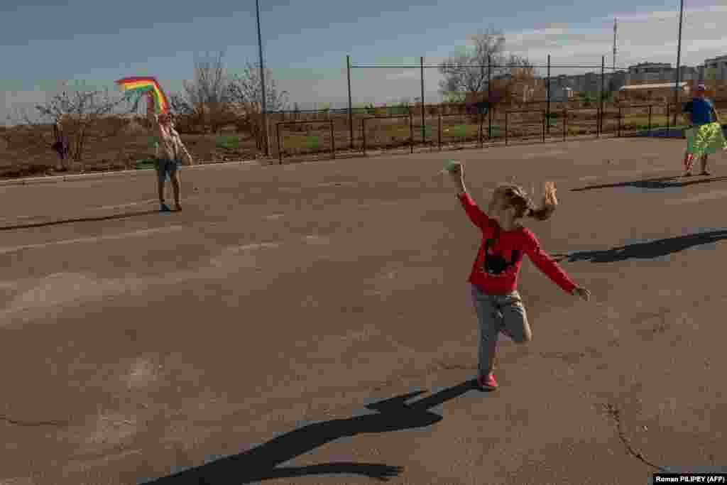 Дівчинка запускає повітряного змія з бабусею під сонячними променями під вечір у Херсоні, 29 жовтня 2023 року  