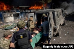 Парамедики несуть пораненого чоловіка в машину швидкої після російського обстрілу ринку в Костянтинівці, 6 вересня 2023 року