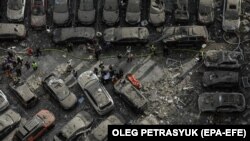 Завалені уламками автомобілі у дворі житлового будинку, пошкодженого осколками ракет у Києві, 24 червня 2023 року