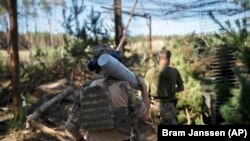 Український військовий несе снаряд до гаубиці на околиці Лиману, 15 серпня 2023 року