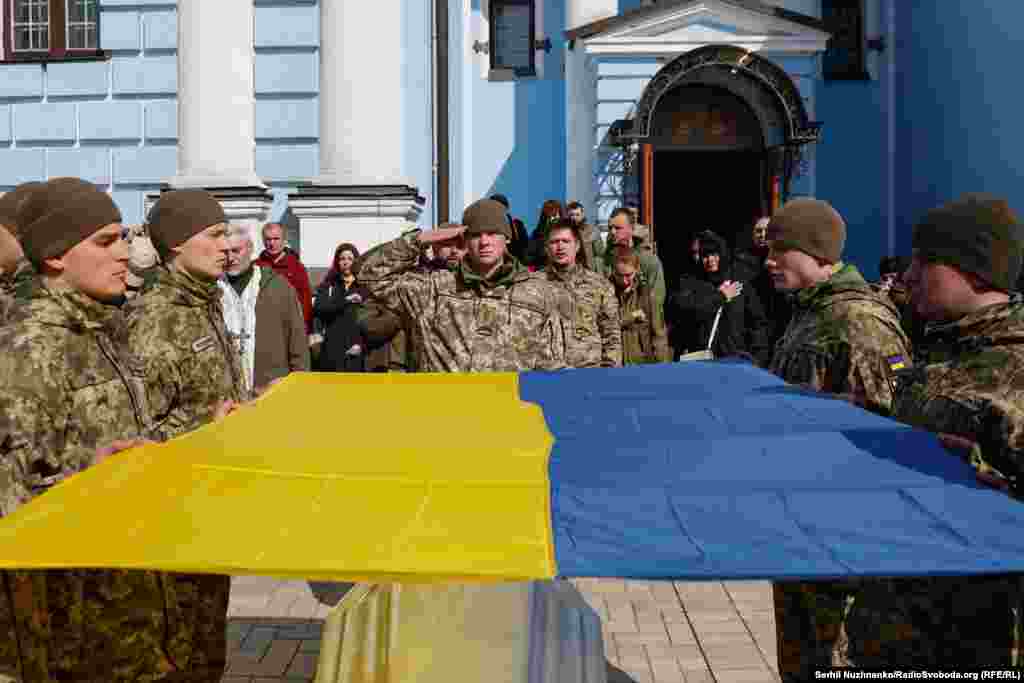 Почесна варта тримає державний прапор України над труною загиблого на російсько-українській війні. Перед входом у Михайлівський собор Києва. 21 березня 2024 року