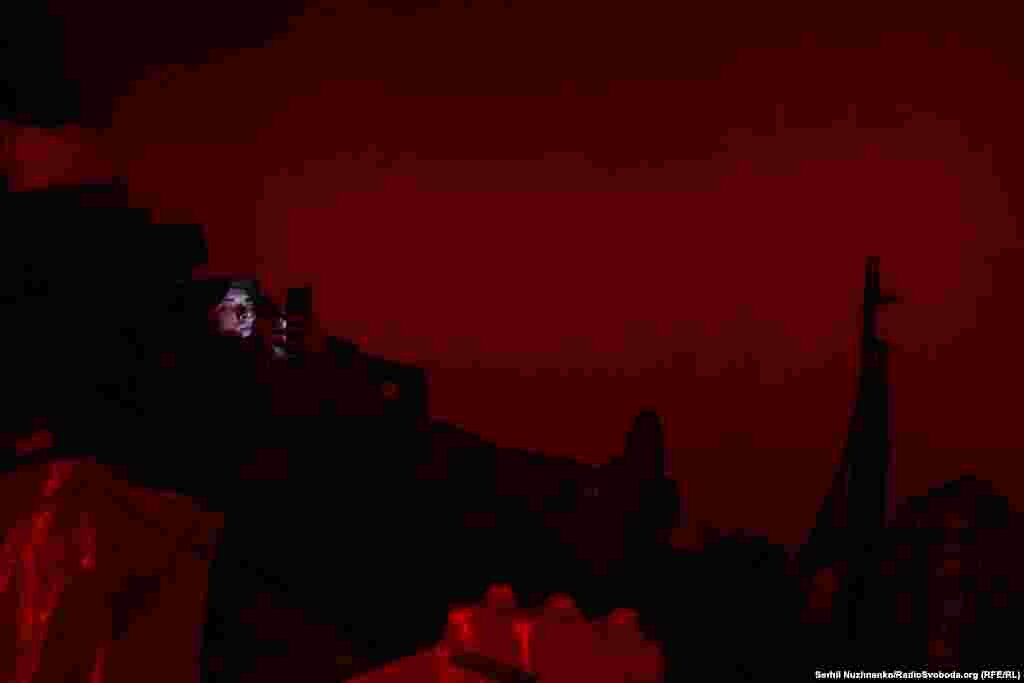 Військовий спілкується з родиною у світлі червоного ліхтарика. Через декілька годин – він і його підрозділ братиме участь у штурмових  діях на північ від Бахмута. Травень 2023 року 