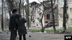 Жителі Авдіївки поруч зі зруйнованим житловим будинком, квітень 2023 року. На лютий 2024 року було відомо, що потреби на відбудову України складають вже майже 486 мільярдів доларів