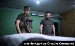 Тоді командувач Сухопутних військ ЗСУ Сирський (ліворуч) доповідає Зеленському на позиції біля лінії фронту на Донеччині, 26 червня 2023 року