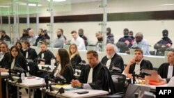 حضور شش متهم پروندۀ یاد شده در یک فضای شیشهای ویژه که پشت سر هیئت منصفه قرار دارد