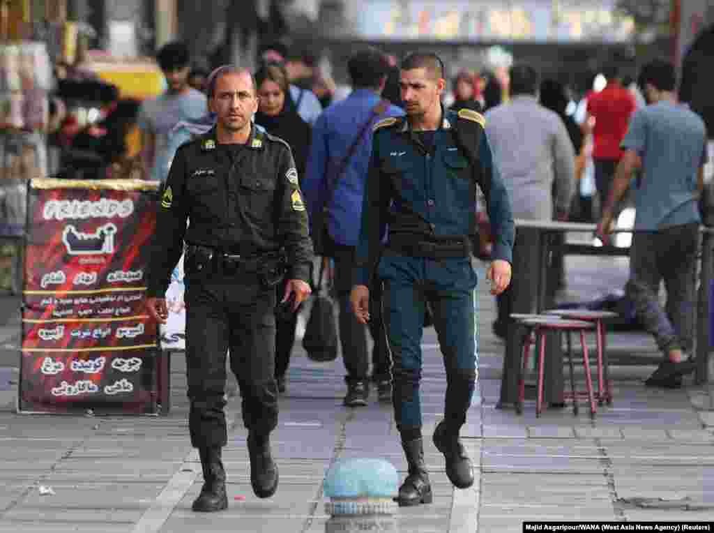 Two policemen walk through Tehran on July 16. The officer on the left is wearing the standard green uniform that is worn by units of the morality police.  
