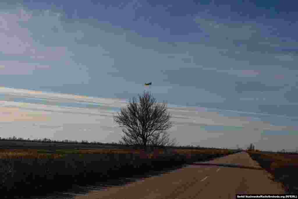 Звільнена територія Миколаївщини. Жовтий шлях під синім небом і український прапор на дереві. Листопад 2022 року 