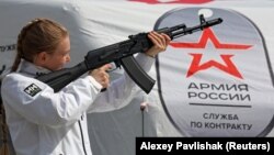 Агітаційниця тримає макет автомата АК-74 на мобільному пункті вербування у лави російської армії в окупованому Росією Сімферополі. Окупований Крим, 15 квітня 2023 року