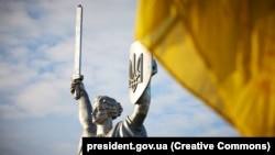 Монумент Батьківщина-Мати із тризубом на щиті і український прапор біля неї. Під час урочистостей у День Державного прапора України. Київ, 23 серпня 2023 року