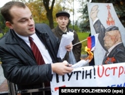 Спалювання прапора Росії на акції протесту біля парламенту України проти будівництва Росією дамби до українського острова Тузла. Київ, 22 жовтня 2003 року. На одному з плакатів зображення мера Москви Юрія Лужкова