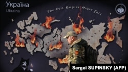 Український військовий проходить повз банер у Києві, Україна.