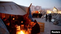 Потерпілі від землетрусу гріються біля вогнища в тимчасовому укритті