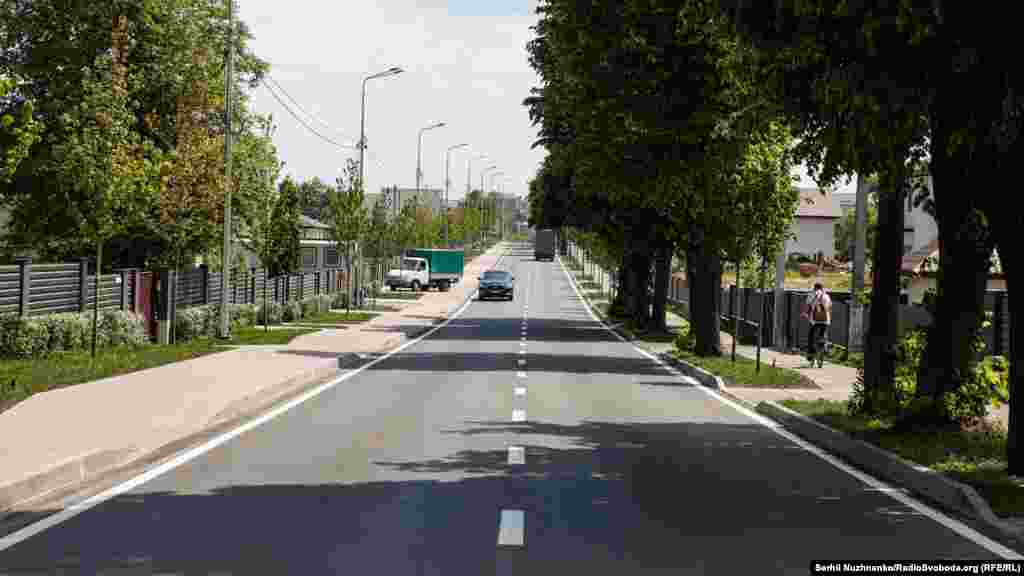 1 березня 2022 року. Буча, вулиця Вокзальна. Саме нею, зазначають відбудовники, тридцятикілометрова колона російської техніки йшла через усе місто до Ірпеня, а звідти планувала йти на Київ, щоб взяти його за 3 дні. Праворуч  вулиця Вокзальна в Бучі у травні 2023 року