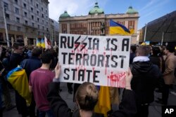 Жінка тримає банер під час мітингу з нагоди річниці вторгнення Росії в Україну в Белграді, Сербія