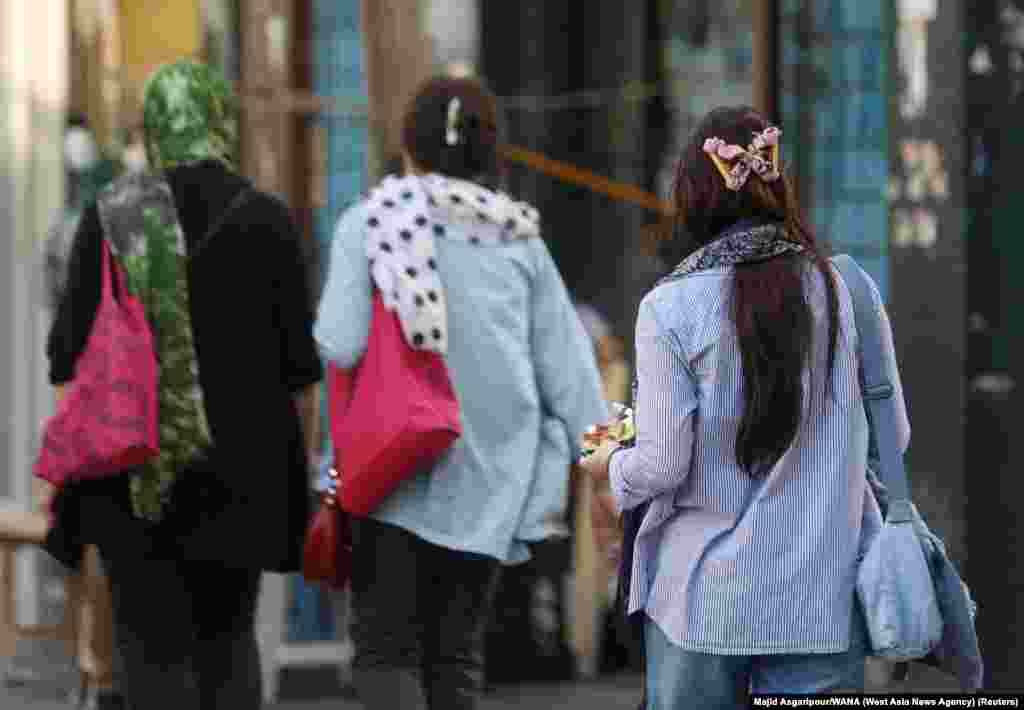 Women walking without head coverings in Tehran on July 16.  Morality police were previously identifiable by the vans with a green stripe that used to transport arrested people, but recent footage from Iranian cities appear to show morality police now operating with unmarked white vans.  