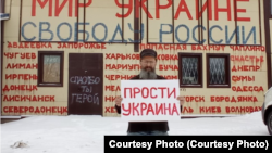 Дмитро Скуріхін із плакатом перед своїм магазином, 24 лютого 2023 року