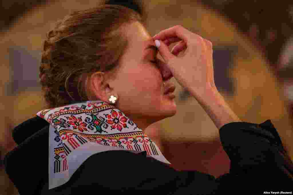 Жінка хреститься під час богослужіння у Володимирському кафедральному соборі в Києві, 16 квітня 2023 року 