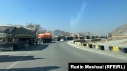 د دې دروازې تړل کېدو له کبله له پيښوره تورخمه ته پر غځېدلې لاره افغانستان ته مالونه وړونکي په سلګونه ټرکونه ولاړ دي.