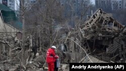 Медпрацівник заспокоює жінку посеред руїн будинків у Запоріжжі. Наслідки російської ракетної атаки. 22 березня 2024 року