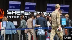 Пассажиры у стоек регистрации в международном аэропорту Шереметьево. Россия, Московская область, 2023 год