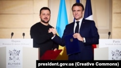 Президент України Володимир Зеленський і президент Франції Емманюель Макрон (праворуч) демонструють підписану Угоду про співробітництво у сфері безпеки між Україною і Францією. Париж, 16 лютого 2024 року