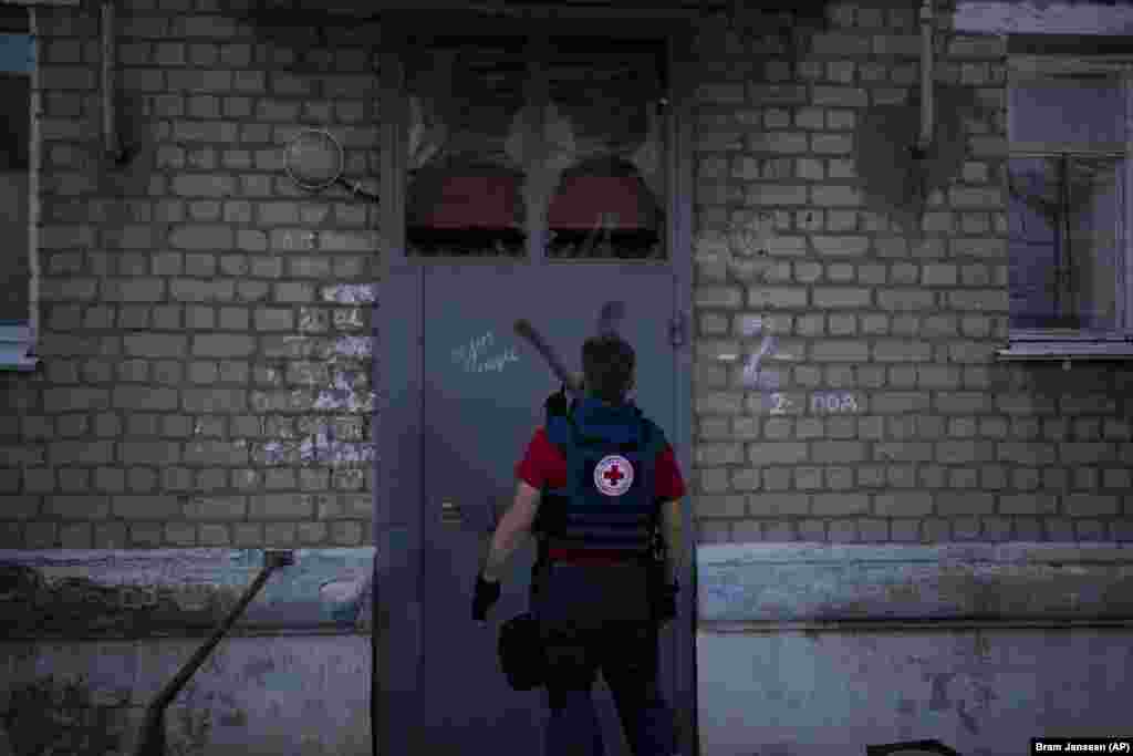 Волонтер Євген Кириченко заходить в житловий будинок, щоб забрати бажаючих евакуюватися. На стіні будинку видно літеру «Z» – символ російської армії у війні з Україною. На початку повномасштабного вторгнення російські війська захопили Куп’янськ. У вересні 2022 року ЗСУ під час контрнаступу відвоювали це українське місто