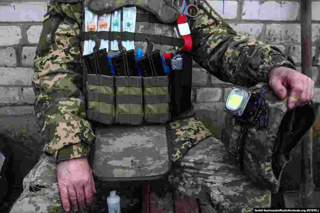 Цей медик має на бронежилеті частину інструментів, необхідних для надання допомоги: катетери, рукавички, турнікет, джгут та ножиці. Поруч із тим – три магазини патронів