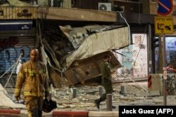 Спасатель перед магазином в Тель-Авиве после попадания ракеты. 7 октября 2023 года