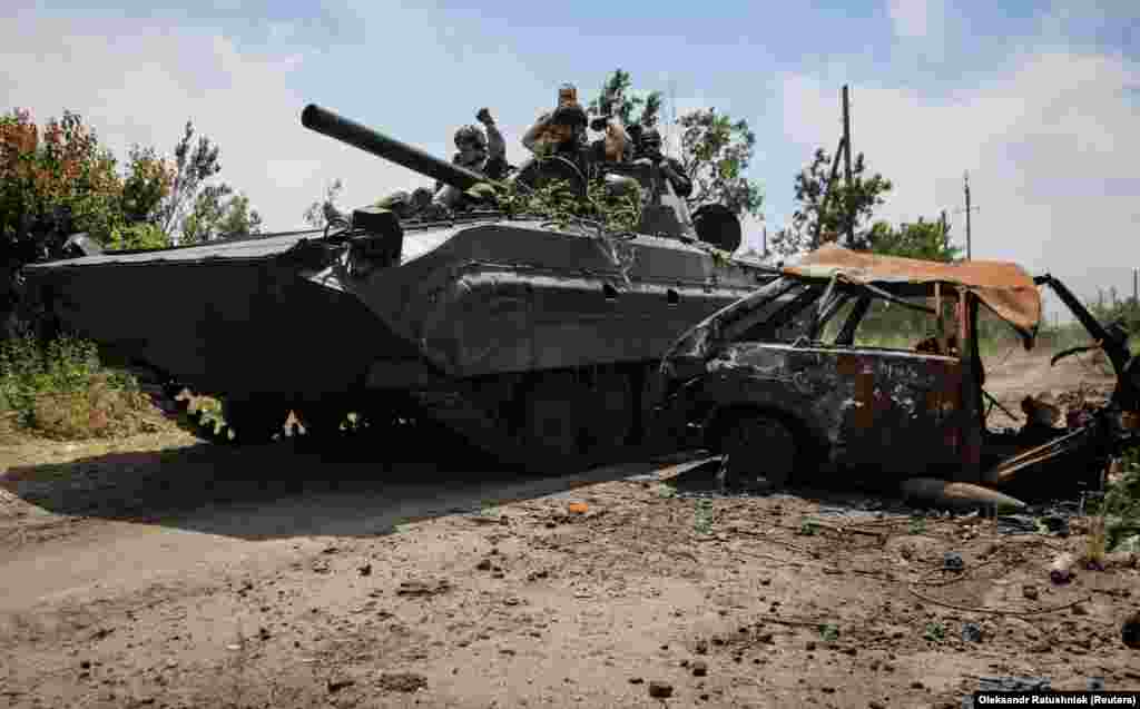 Українські військові на бойовій машині піхоти БМП-1 проїжджають повз знищений автомобіль. Нескучне, Донецька область, 13 червня 2023 року
