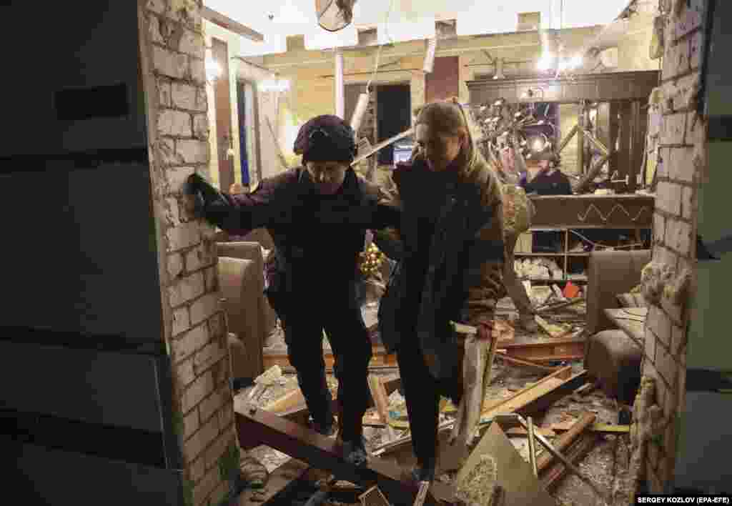 Поліцейський допомагає жінці, яка проживала в готелі, дістатися зі зруйнованої ракетним обстрілом будівлі на вулицю. Харків, 11 січня 2023 року. Один із поранених перебуває у «дуже важкому стані», сказав Ігор Терехов, додавши, що «серед постраждалих є турецькі журналісти»  