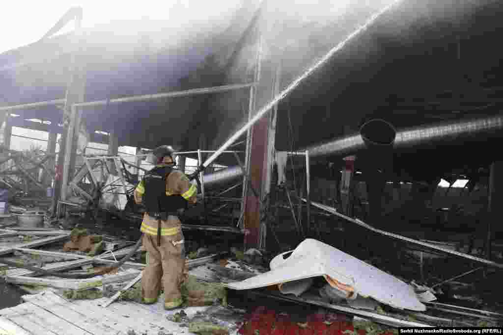 Рятувальник гасить пожежу у супермаркеті після ракетного удару РФ  