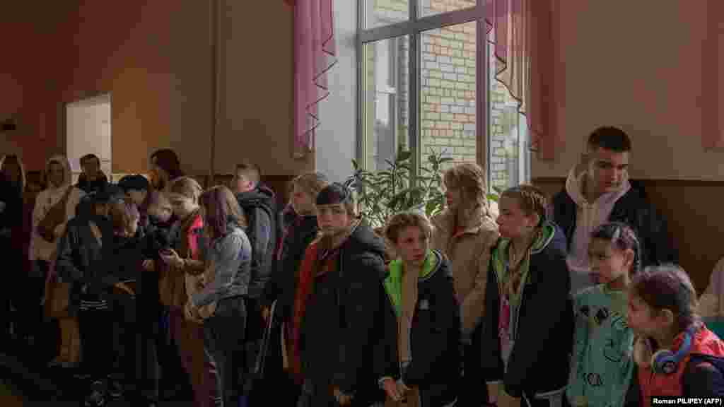 Діти збираються перед евакуацією, Херсон, 30 жовтня 2023 року. Надія Кондраткова, мати двох доньок, яка вперше розлучається зі своїми дітьми, тремтіла від страху, а її очі наповнилися слізьми. «Їм потрібно відпочити подалі від вибухів і сирен», – пояснила Кондраткова своє рішення відправити своїх доньок з Херсону. «Вони виснажені – каже вона. – Вони вже не можуть спати і кричать ночами»