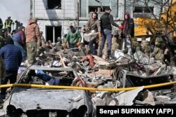 Місцеві жителі і рятувальники розбирають завали на місці ракетного удару в Умані, 28 квітня 2023 року