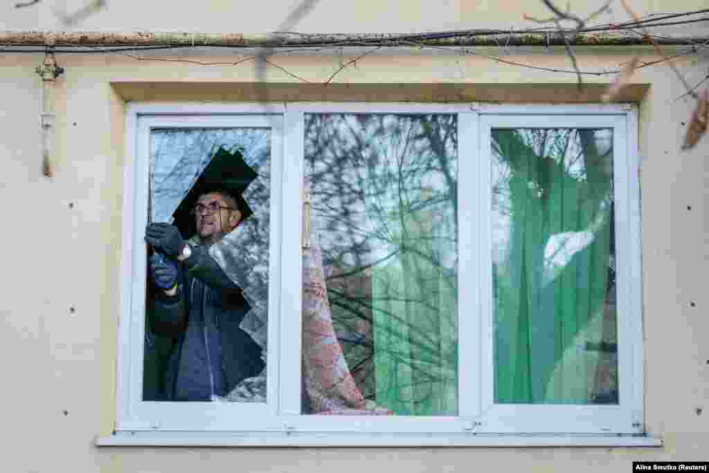 Місцевий житель виймає бите скло з вікна своєї квартири, яке було пошкоджене під час атаки. Попри докази і свідчення, Москва від початку повномасштабного вторгнення заперечує цілеспрямовану атаку на цивільних.
